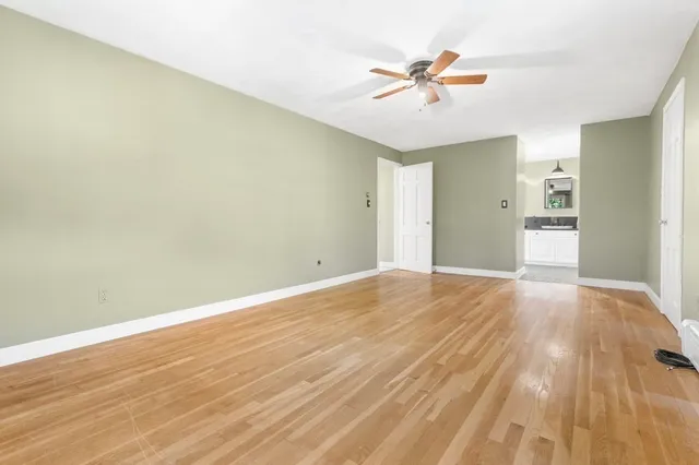 an empty room with wooden floor and ceiling fan