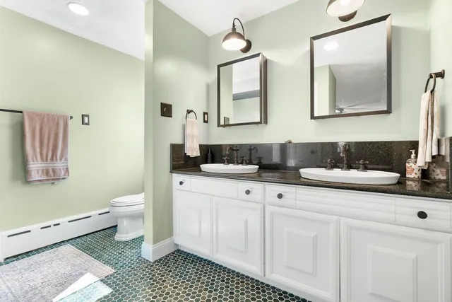 a bathroom with a double vanity sink mirror and toilet