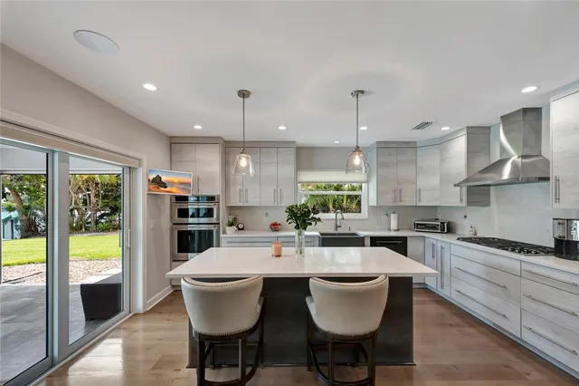 a kitchen with a dining table wooden floor and a stainless steel appliances