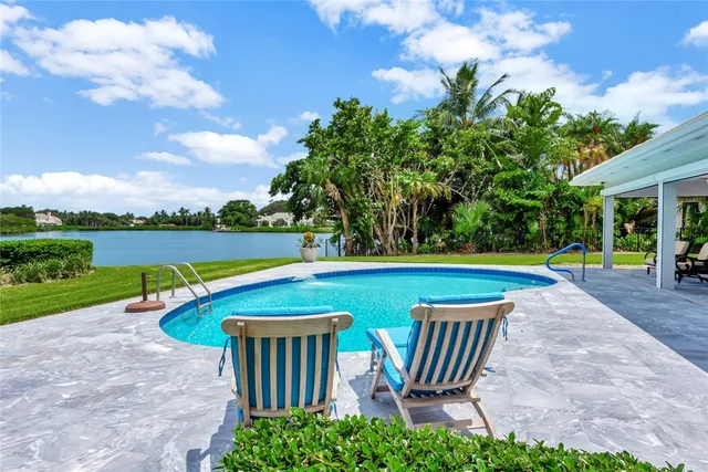 a view of swimming pool with lawn chairs and a yard