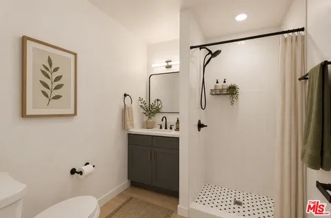 a bathroom with a shower sink vanity mirror and toilet