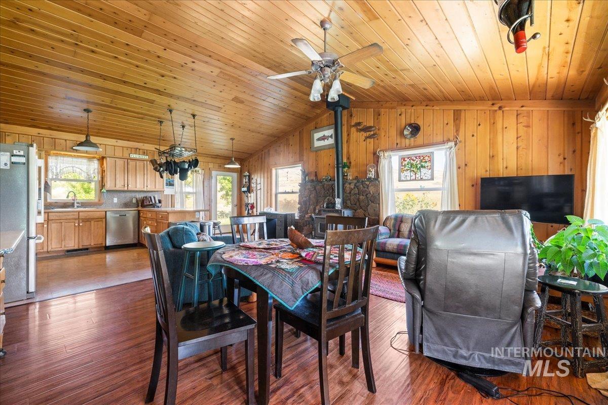 2128 Jackson Creek Road Council, ID 83612 - Photo 17 of 50 Dining area featuring dark wood-style floors, healthy amount of natural light, lofted ceiling, a wood stove, and wooden walls