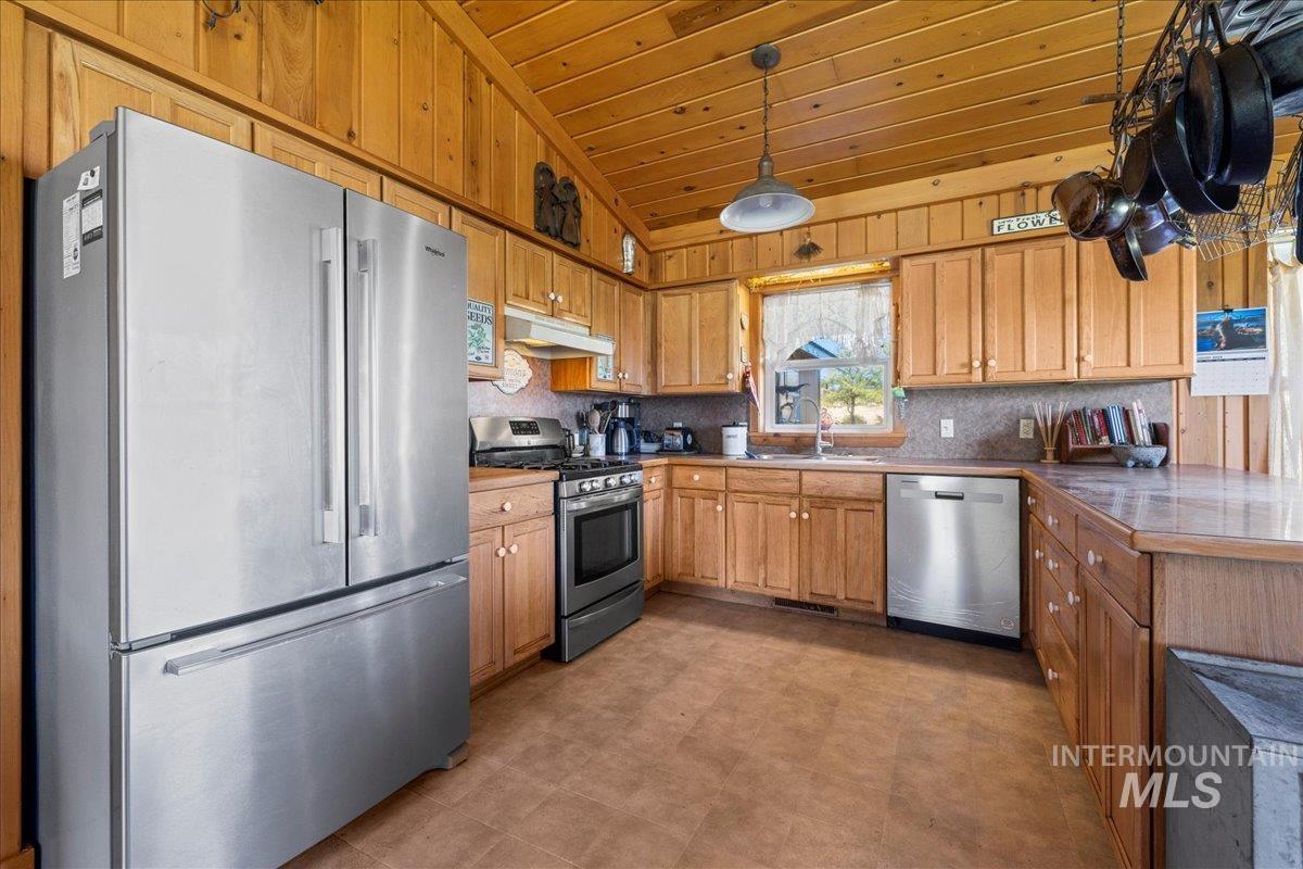 2128 Jackson Creek Road Council, ID 83612 - Photo 19 of 50 Kitchen featuring appliances with stainless steel finishes, vaulted ceiling, brown cabinetry, a peninsula, and wooden ceiling