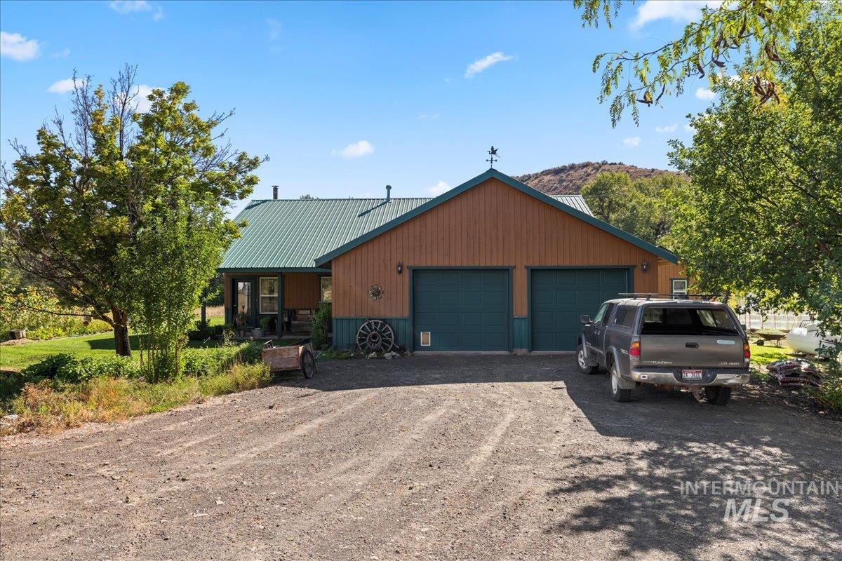 2128 Jackson Creek Road Council, ID 83612 - Photo 47 of 50 View of front facade with driveway, a metal roof, a garage, and covered porch