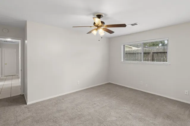 an empty room with windows and fan