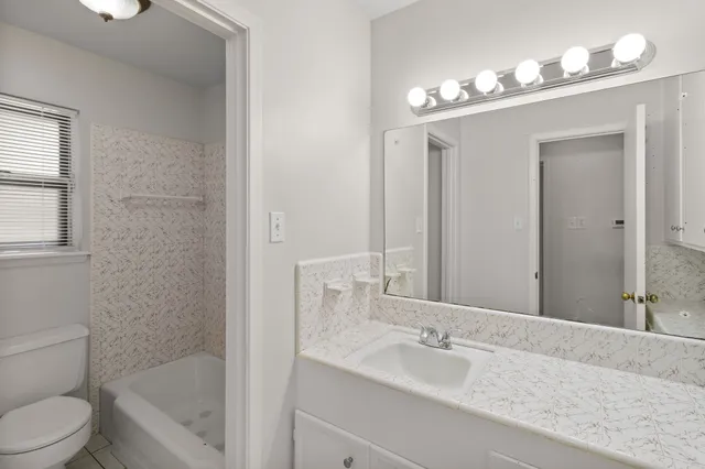 a bathroom with a granite countertop sink a toilet and bathtub