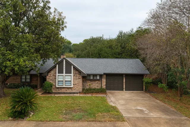 a front view of a house with a garden and trees
