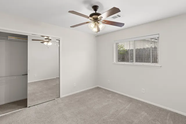 an empty room with windows and fan