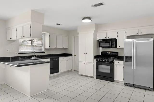 a kitchen with granite countertop white cabinets and stainless steel appliances