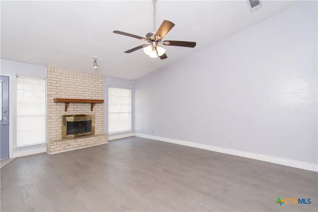an empty room with windows and fireplace