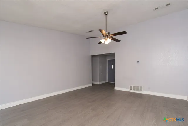 a view of an empty room with a chandelier fan