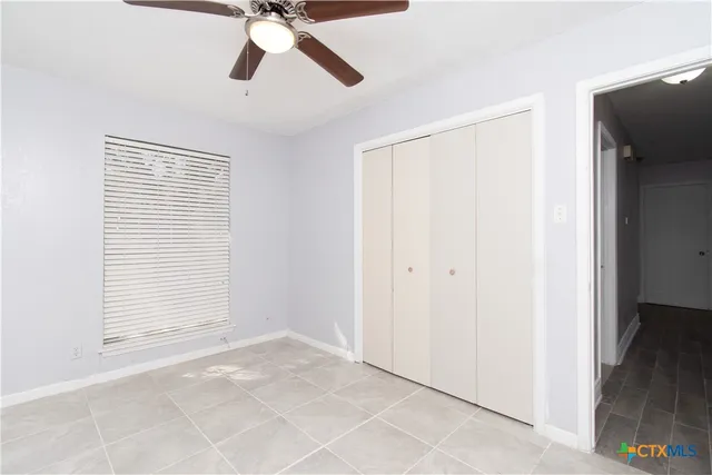 a view of an empty room with chandelier fan and a window
