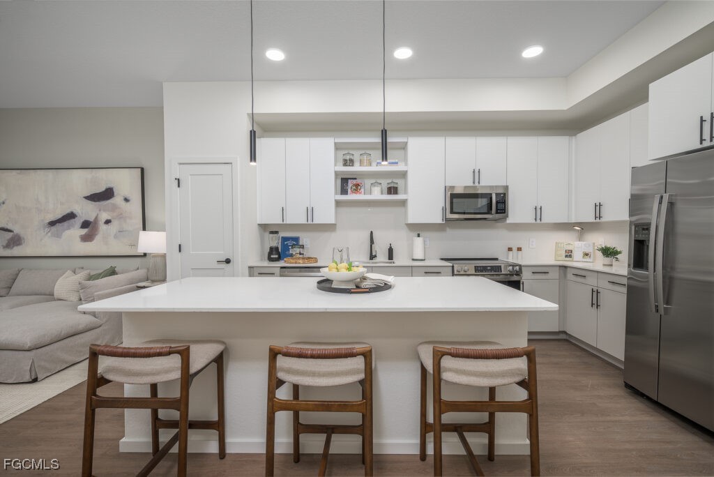 8552 Collier Boulevard, Unit RAVELLO Naples, FL 34114 - Photo 3 of 20 a kitchen with stainless steel appliances a table chairs refrigerator and microwave
