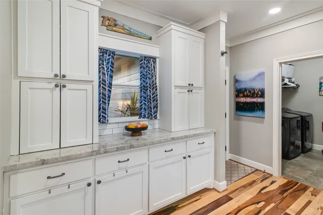 a hallway with white cabinets and wooden floor