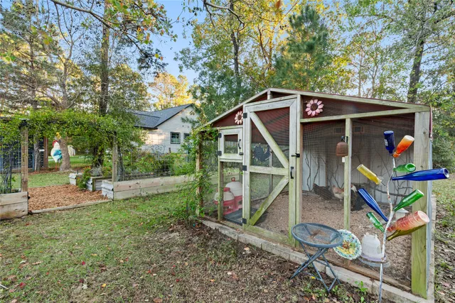 a view of a small house with wooden fence and large trees