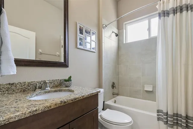 a bathroom with a granite countertop tub sink toilet and mirror