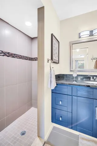 a bathroom with a granite countertop sink a mirror and a shower