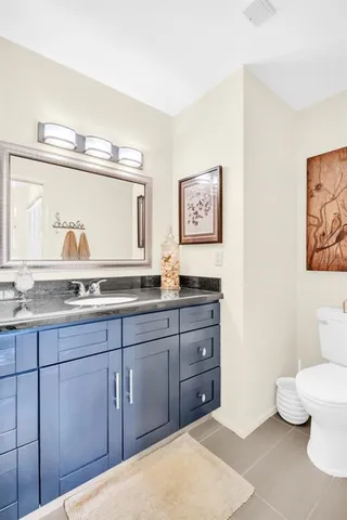 a bathroom with a granite countertop toilet sink and mirror