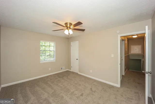 an empty room with windows and a chandelier fan