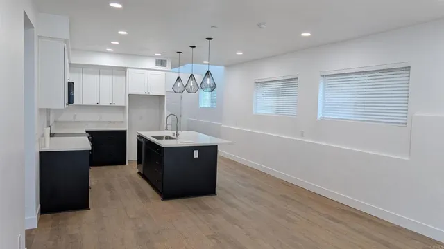 a kitchen with stainless steel appliances granite countertop a sink dishwasher a stove and a refrigerator with wooden floor