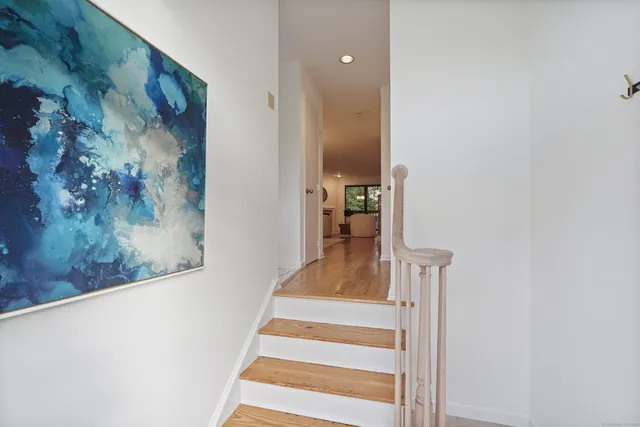 a view of a hallway with wooden floor and a staircase