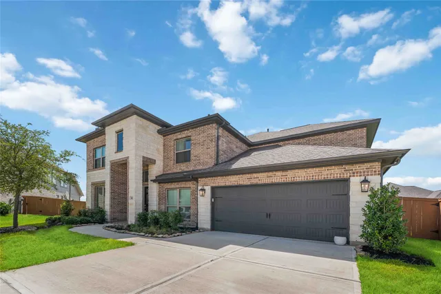 a view of a white house next to a yard with big trees
