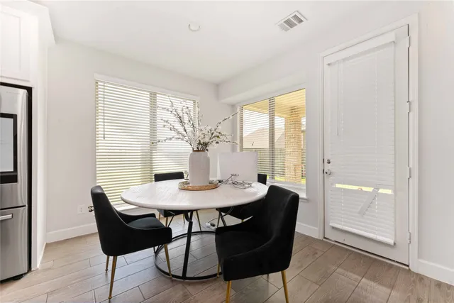 a kitchen with stainless steel appliances a dining table chairs and wooden floor