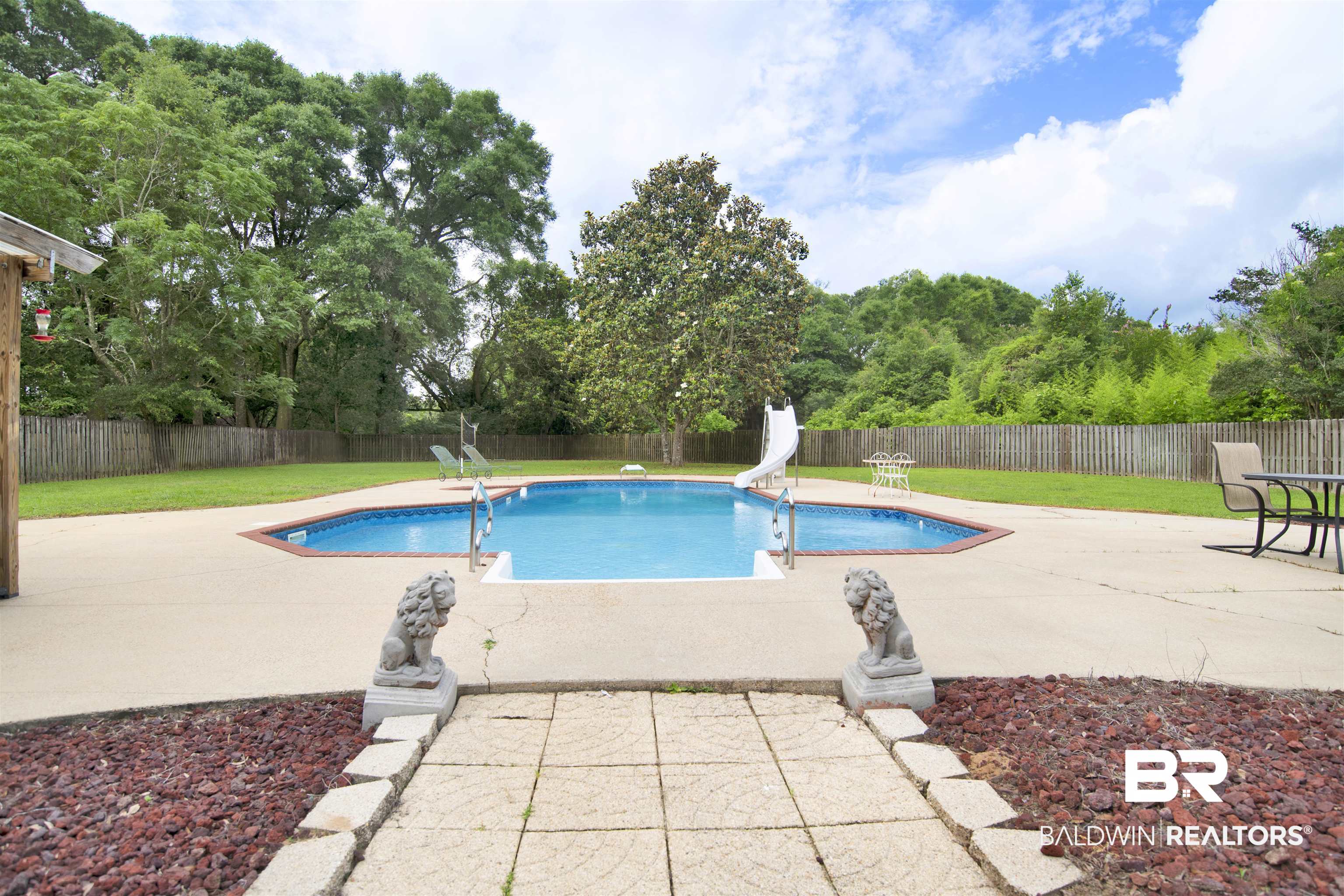 8847 Dawes Lake Road South Mobile, AL 36619 - Photo 40 of 47 Expansive outdoor living area featuring a blue-tiled swimming pool with a white slide and metal railings, surrounded by a concrete patio
