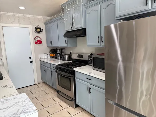 a kitchen with stainless steel appliances granite countertop a refrigerator a stove and a sink