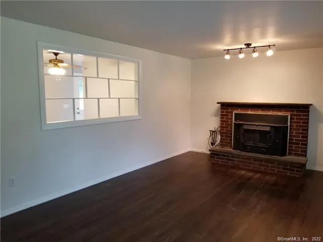an empty room with wooden floor fireplace and windows