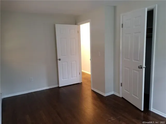 an empty room with wooden floor & windows