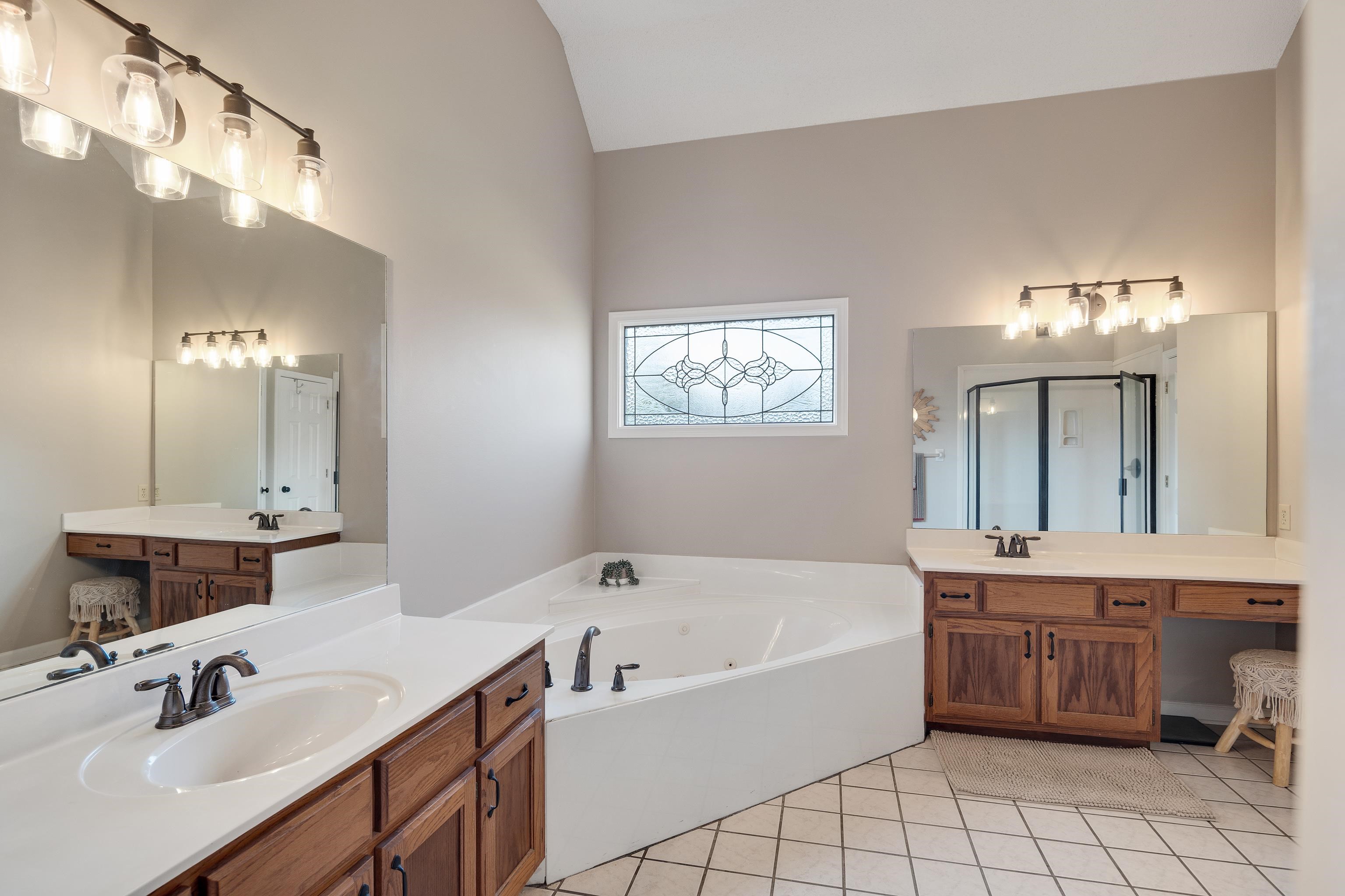 540 Whitney Way Collierville, TN 38017 - Photo 14 of 22 Bathroom with two vanities, a jetted tub, light tile patterned flooring, and vaulted ceiling