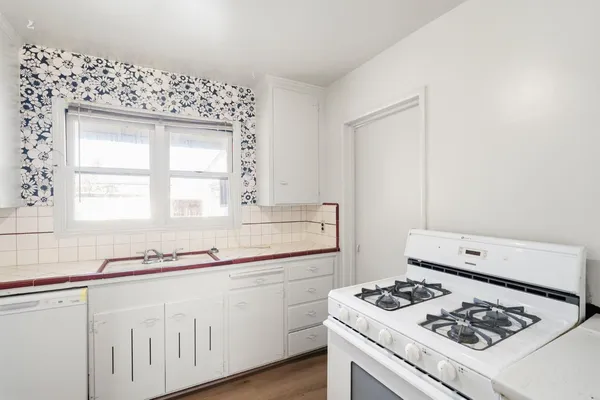 a kitchen with white cabinets stove and sink