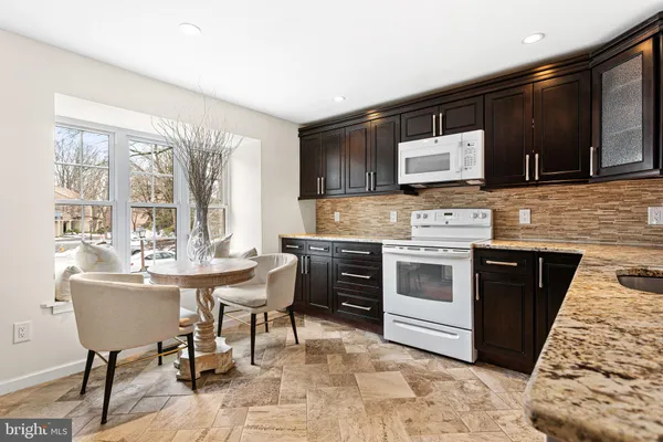 a kitchen with stainless steel appliances kitchen island granite countertop a sink and stove top oven with wooden floor