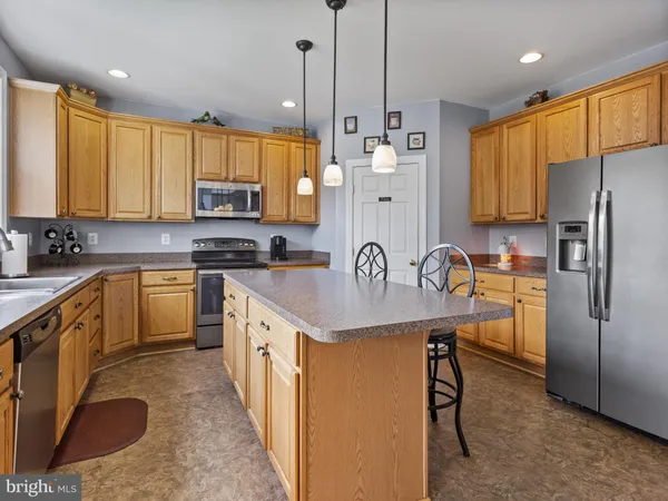 a kitchen with a refrigerator a sink a stove a microwave a center island and cabinets