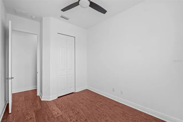 an empty room with wooden floor and fan
