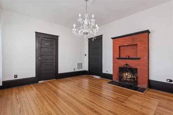 a view of an empty room with wooden floor fireplace and a window