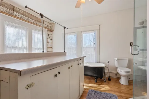 a bathroom with a granite countertop sink a toilet a mirror and a glass door shower