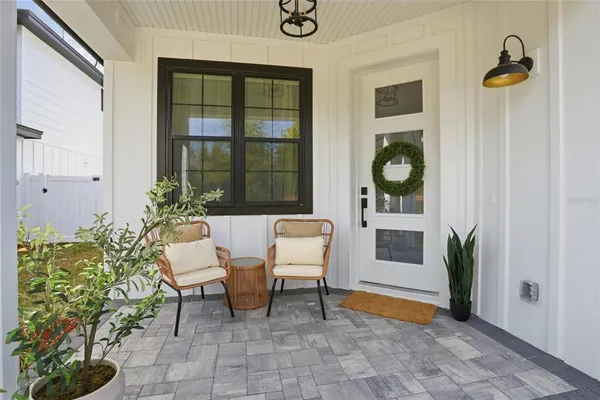 a balcony with couple of chairs and a potted plant
