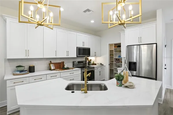 a kitchen with stainless steel appliances a sink a stove a microwave a refrigerator a stove and cabinets