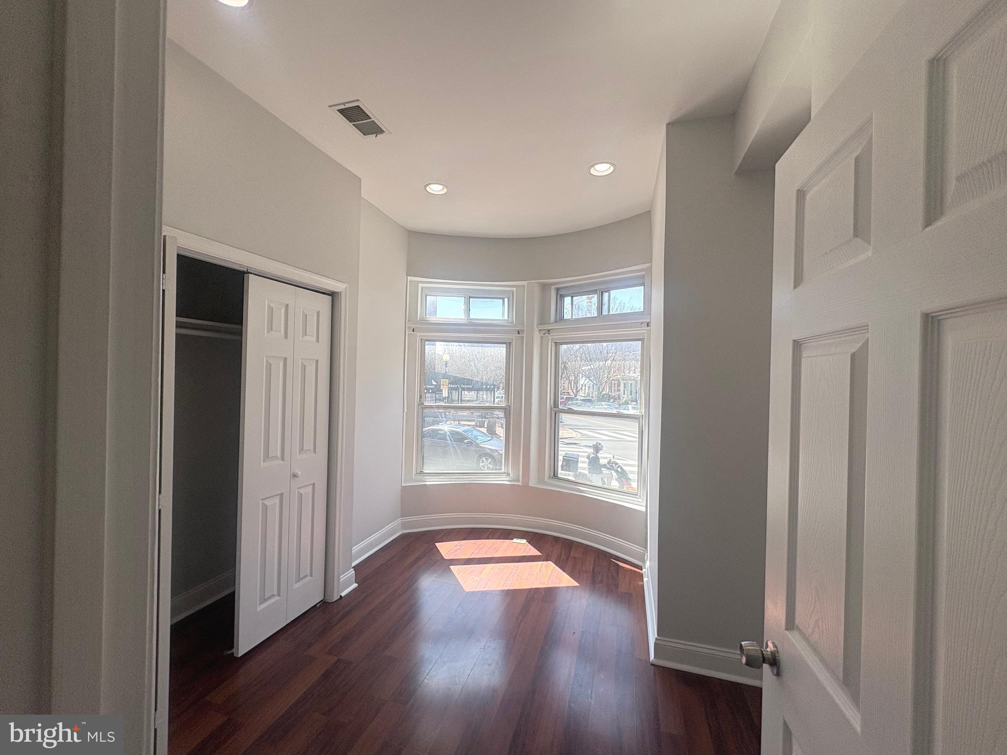 a view of empty room with wooden floor and window