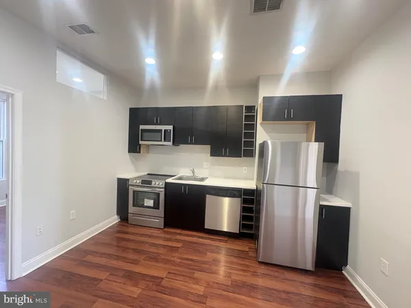 a kitchen with stainless steel appliances granite countertop a refrigerator a stove top oven a sink with wooden floor