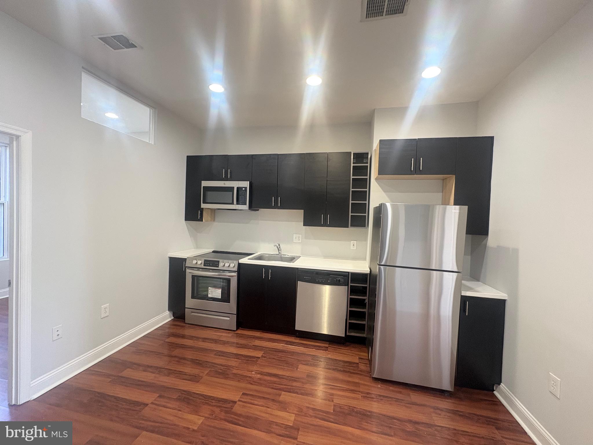 543 Florida Avenue Northwest, Unit 2 Washington, DC 20001 - Photo 6 of 11 a kitchen with stainless steel appliances granite countertop a refrigerator a stove top oven a sink with wooden floor