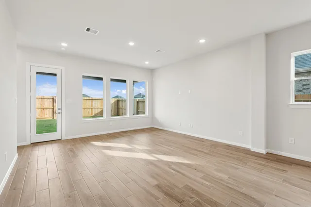 an empty room with wooden floor closet and windows