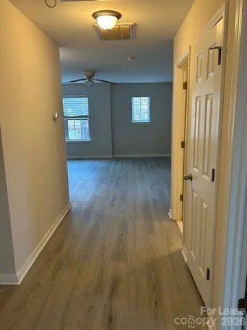 a view of a hallway with wooden floor and a living room