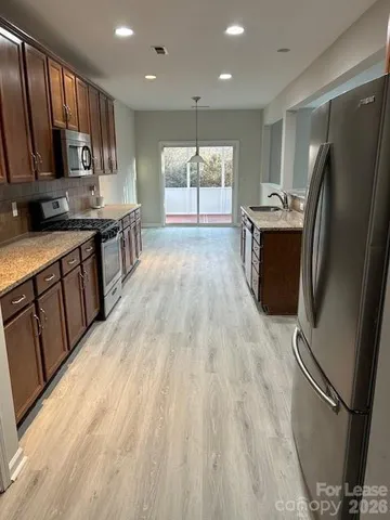 a kitchen with stainless steel appliances granite countertop a refrigerator a stove top oven a sink and dishwasher