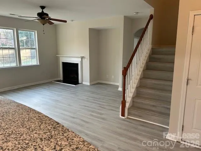 a view of an empty room with wooden floor fireplace and a window