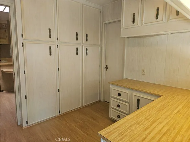 a view of a hallway with wooden floor and a bathroom