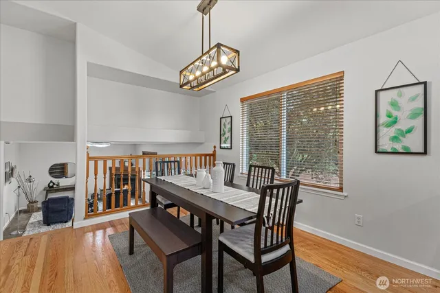 a dining room with wooden floor a chandelier a wooden table and chairs