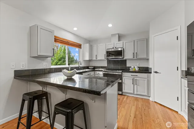 a kitchen with kitchen island a stove a sink and a refrigerator with wooden floor